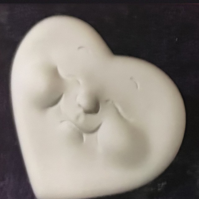 Heart face, right side, eyes closed, number 65, unpainted bisque on black velvet