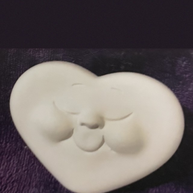 Heart face, up right, eyes closed, number 67, unpainted bisque on black velvet